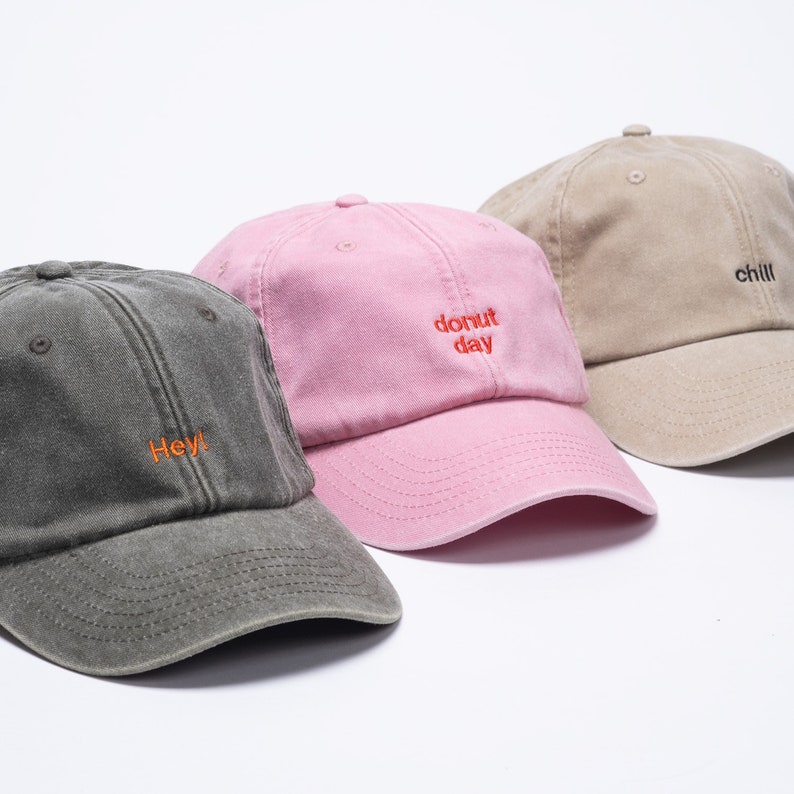 A selection of vintage washed out cap with custom embroidery on the front. Featuring pink cap with red embroidery, black cap with orange thread and khaki cap with black lettering