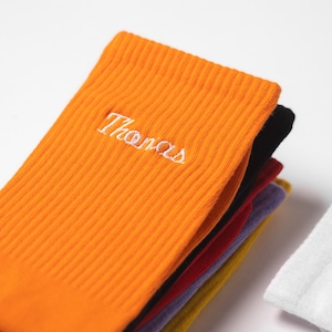 A stack of personalised embroidered socks in multiple colours.