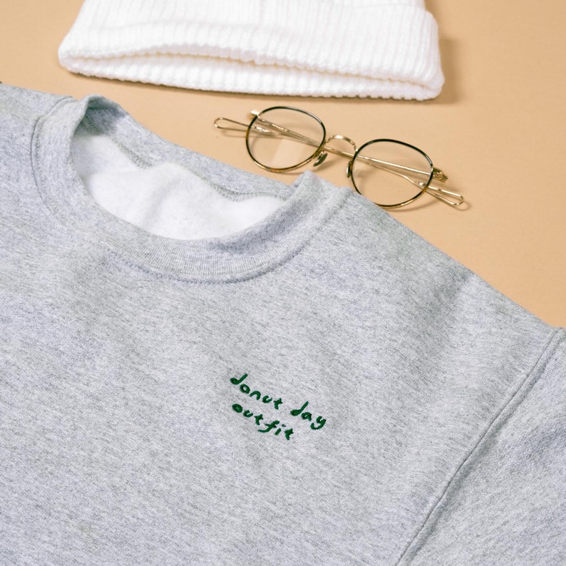 Grey embroidered sweatshirt saying donut day in green colour with glasses and white beanie capsule outfit