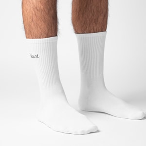 Side angle of male foot wearing white ribbed knit cotton socks with custom embroidered name on the side in black