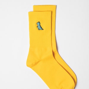 Swatch of yellow ribbed unisex socks with dino embroidery
