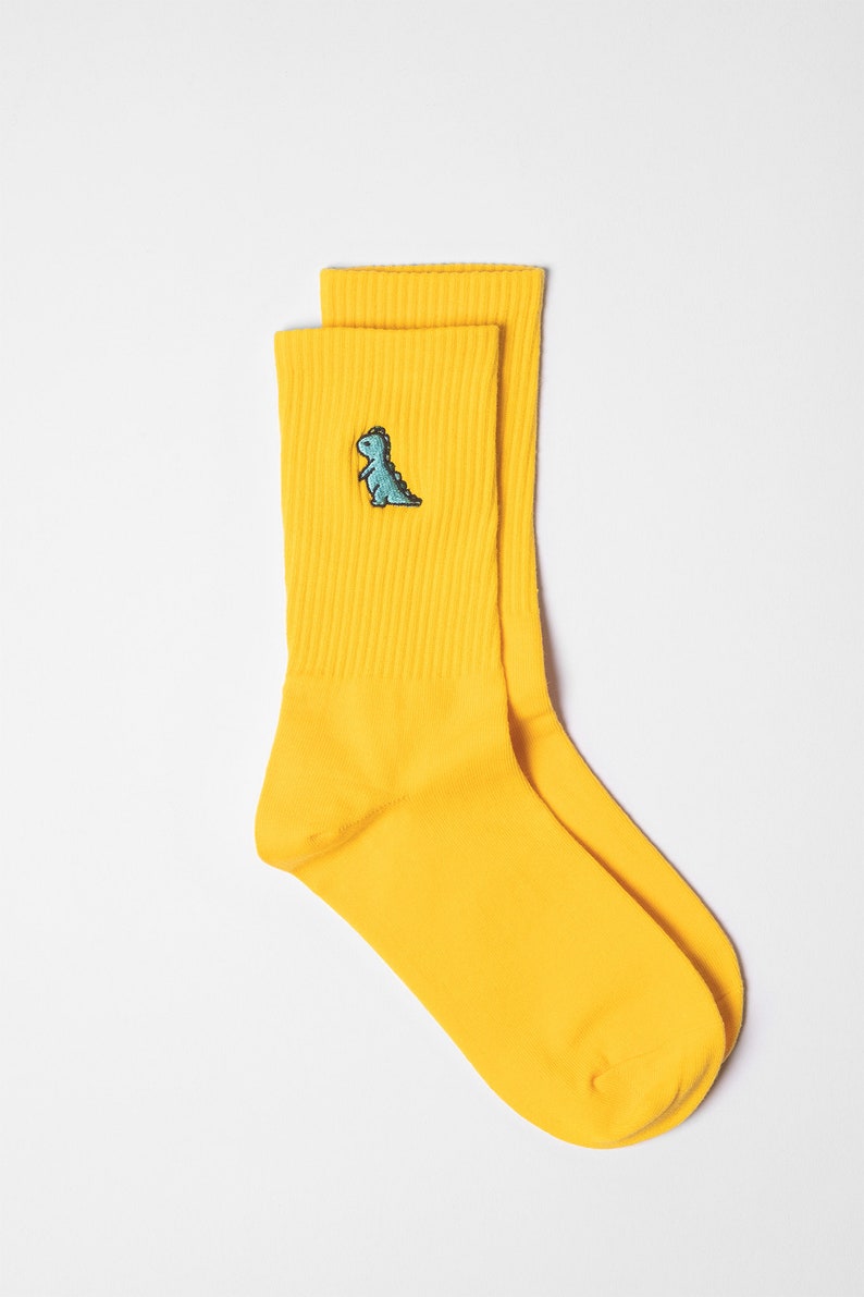 Swatch of yellow ribbed unisex socks with dino embroidery