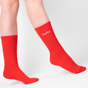 Womans red sockson a model with custom name embroidery on the side. Red socks have white name Sophia embroidered on them