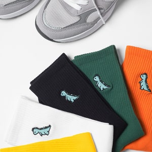 Ribbed cotton socks featured in yellow, white, black, green and orange colours with vibrant little dinosaur embroidery