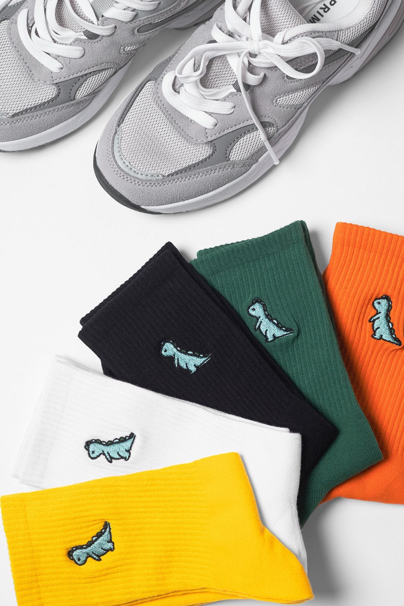 Ribbed cotton socks featured in yellow, white, black, green and orange colours with vibrant little dinosaur embroidery