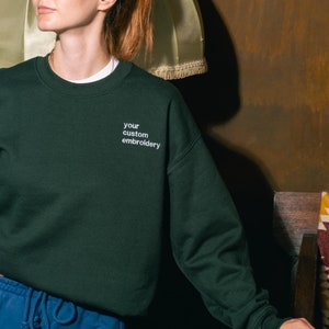Young woman wearing dark green sweatshirt with custom personalised embroidery