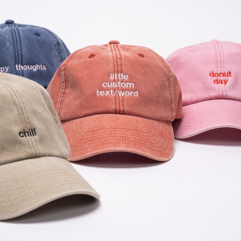 Vintage style cap with custom text embroidered on the front of it. Caps are orange, pink, khaki and denim colours.