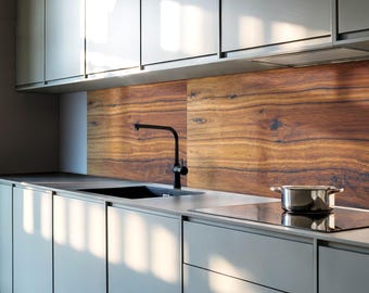 May include: A modern kitchen with gray cabinets and a wood-grain backsplash. A black faucet is mounted above a stainless steel sink. A black electric stovetop is to the right of the sink. A silver pot is on the stovetop.