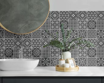 May include: A bathroom with a black and white patterned tile backsplash. A round mirror hangs above a white porcelain sink. A small plant in a white vase sits on the counter next to a wooden tray with decorative items.