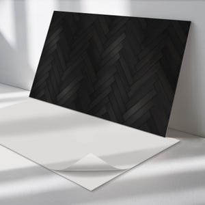 May include: A black and white herringbone patterned self-adhesive contact paper. The contact paper is shown partially peeled back from a white backing sheet.