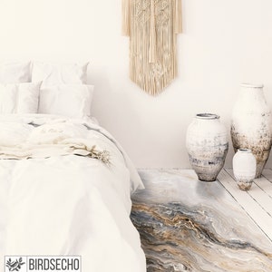 May include: A white bed with white bedding and a white throw blanket. The bed is in a room with white walls and a white floor. There are three white ceramic vases on the floor, and a macrame wall hanging above the bed.