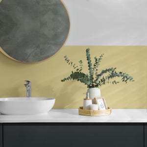 May include: A bathroom vanity with a white ceramic sink, a chrome faucet, and a round mirror with a wood frame. A wicker tray holds a white ceramic vase with eucalyptus branches, a white ceramic soap dispenser, and a white ceramic candle.