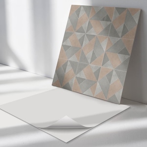 May include: A close-up of a decorative tile with a geometric pattern of overlapping triangles in shades of grey and brown. The tile has a textured surface.