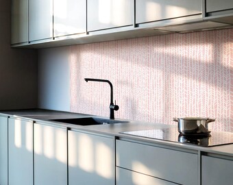 May include: A modern kitchen with gray cabinets and a pink patterned backsplash. A black faucet is mounted above a black sink. A black stovetop is visible in the foreground.