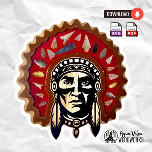 May include: A wooden wall decor featuring a Native American chief with a headdress made of arrowheads. The headdress is surrounded by a brown wooden frame with a red background. The chief's face is black and white, and he has a serious expression. The text "Aqua Vitae Woodworks Est. 2021" is visible in the bottom right corner.
