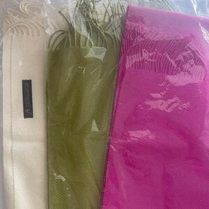 May include: Three scarves in different colors: white, green, and pink. The scarves are made of a soft, lightweight fabric and have a fringed edge.