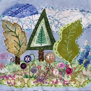 Puede incluir: Un fondo de tela azul con una aplicación de árbol verde, marrón y amarillo. El árbol está rodeado de hojas verdes, flores azules y botones coloridos.