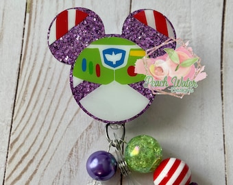 Puede incluir: Portagafete con forma de Mickey Mouse de purpurina morada con un diseño de Buzz Lightyear. El portagafete tiene un carrete de gafete retráctil plateado con una cuenta morada, una cuenta verde y blanca y una cuenta roja y blanca a rayas. El portagafete también tiene un borla morada.