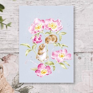 Puede incluir: Ilustración en acuarela de dos ratones entre flores rosas y hojas verdes sobre un fondo azul claro. La obra presenta pinceladas detalladas y un tema caprichoso inspirado en la naturaleza. Las flores tienen centros amarillos.