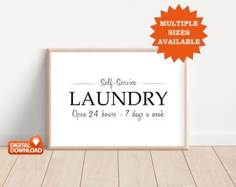 May include: A framed print with the words "Self-Service LAUNDRY" in a bold, black font. Below, it reads "Open 24 hours - 7 days a week." An orange burst graphic states "MULTIPLE SIZES AVAILABLE." A small orange graphic reads "DIGITAL DOWNLOAD."