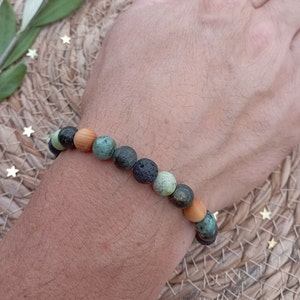 Peut inclure: Un bracelet composé de perles vertes, noires et brunes. Le bracelet est porté au poignet.