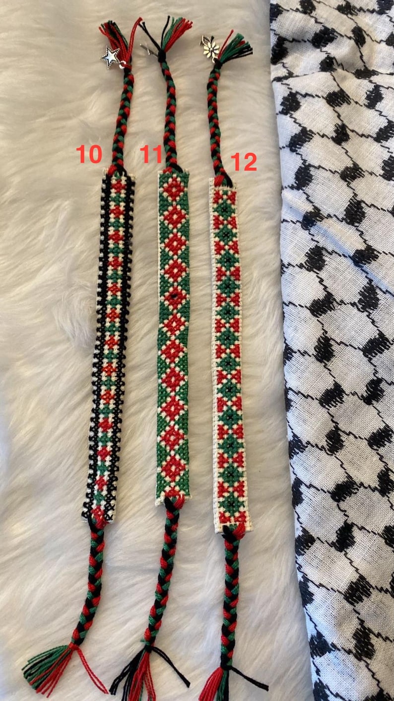May include: Three friendship bracelets made with red, green, white and black thread. The bracelets are labelled 10, 11 and 12.