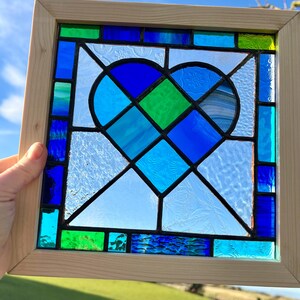 May include: A stained glass window featuring a blue and green heart design framed in natural wood.