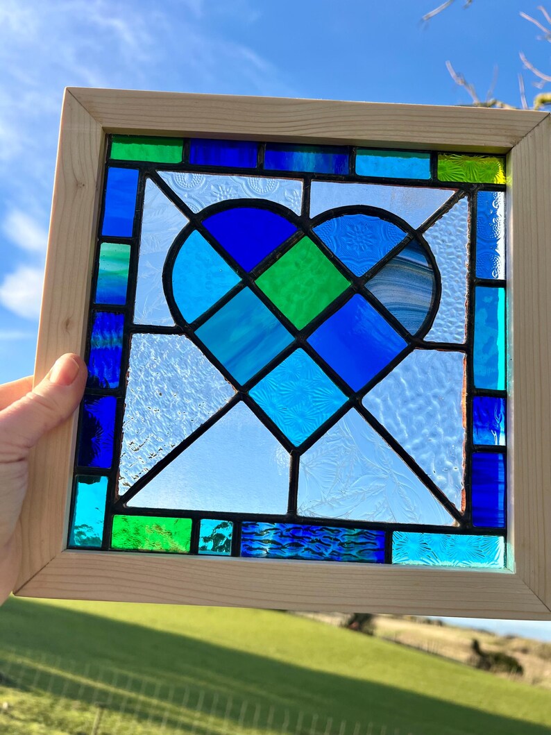 May include: A stained glass window featuring a blue and green heart design framed in natural wood.