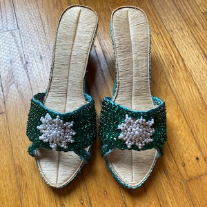May include: A pair of green and white beaded sandals with a woven straw sole.