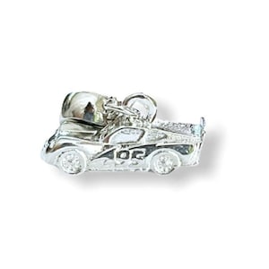 May include: A silver-colored charm in the shape of a race car with the number "02" on the side. The charm has a detailed design, including wheels and a roll cage. The charm is likely made of a metal such as sterling silver.