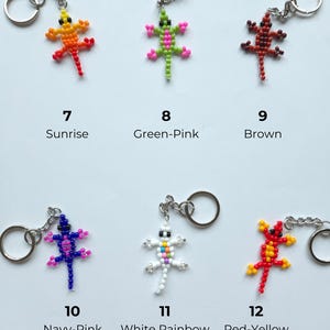 May include: Six lizard-shaped keychains made of small beads, each with a metal ring. The designs are labeled 7 Sunrise (orange-yellow), 8 Green-Pink, 9 Brown, 10 Navy-Pink, 11 White Rainbow, and 12 Red-Yellow, showcasing various color combinations.