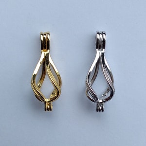 May include: Two silver and gold cage pendants for necklaces or bracelets. The cages are designed to hold a small pearl or other charm.