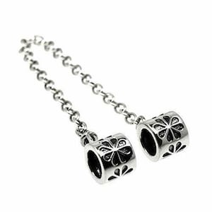 May include: A silver chain with two silver charms. Each charm is a cylinder with a flower design.