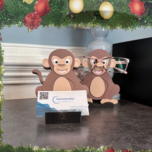 May include: Two brown monkey figurines with glasses, one wearing pink glasses, holding a business card with the text "Functionally Fun" and a QR code.