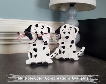 May include: Two black and white Dalmatian dog-shaped glasses holders. The holder on the left has a pair of pink glasses on it.  Multiple Colour Combinations Available.