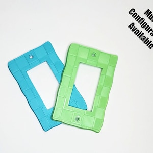 May include: Two light switch covers, one is turquoise blue and the other is light green. Both have a woven pattern and a rectangular opening for a light switch.