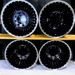 Puede incluir: Cuatro ruedas de cami&oacute;n negras y plateadas con un dise&ntilde;o de turbina. Las ruedas est&aacute;n dispuestas en dos filas de dos, con la fila superior ligeramente desplazada de la fila inferior.