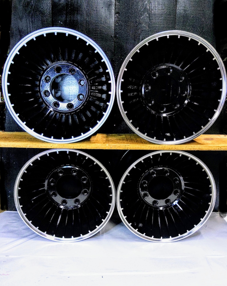 Puede incluir: Cuatro ruedas de cami&oacute;n negras y plateadas con un dise&ntilde;o de turbina. Las ruedas est&aacute;n dispuestas en dos filas de dos, con la fila superior ligeramente desplazada de la fila inferior.