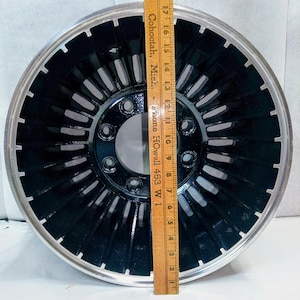 Puede incluir: Una rueda de coche negra y plateada con un dise&ntilde;o de radios. La rueda tiene un di&aacute;metro de 15 pulgadas.