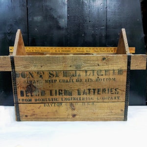 Peut inclure: Une caisse en bois avec des sangles en métal noir et le texte "Don't Steal  Batteries  Always Keep Crate on its Bottom  Delco Light Batteries  From Domestic Engineering Company, Dayton, Ohio, U.S.A."