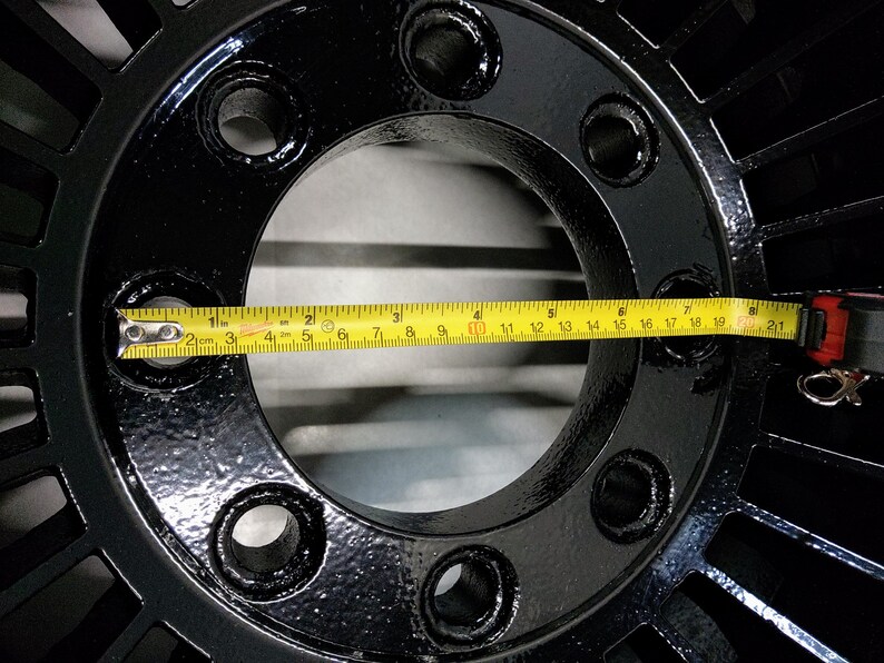 Puede incluir: Primer plano de una rueda de metal negro con un di&aacute;metro de 17 pulgadas, medida con una cinta m&eacute;trica amarilla.