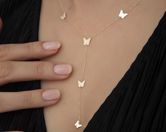 May include: A gold necklace with a delicate chain and multiple butterfly charms. The necklace is layered with a shorter chain and a longer chain with a dangling butterfly charm.