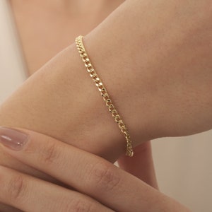 Könnte beinhalten: Ein goldenes Kettenarmband mit einem Curb-Kettenglied-Design.