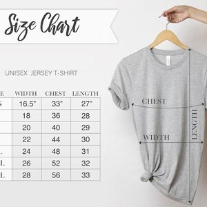 Puede incluir: Una camiseta unisex de punto de color gris claro colgada de una percha de madera. La imagen incluye una tabla de tallas con medidas en cm para el ancho, el pecho y el largo. La tabla enumera tallas de XS a 3XL.
