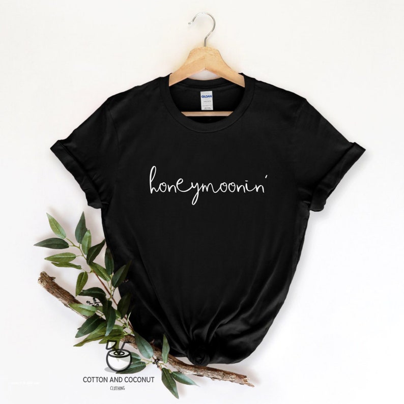 May include: Black t-shirt with the text "honeymoonin'" in white script font.