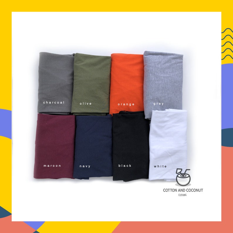 May include: A selection of eight folded t-shirts in different colors, including charcoal, olive, orange, grey, maroon, navy, black, and white. The t-shirts are arranged in two rows of four. The text "COTTON AND COCONUT CLOTHING" is printed below the t-shirts.