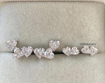 May include: A pair of earrings and a single earring with heart-shaped stones. The earrings are arranged in a row, with the text "IceBling Jewelry" visible in the background. The earrings are set in a light-colored box.