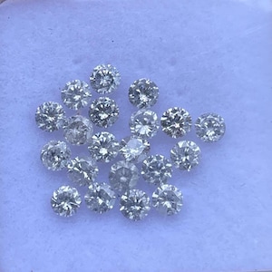 May include: A selection of round-cut diamonds, each with multiple facets, presented on a white surface. The diamonds are clear and sparkling, reflecting light. The image highlights the brilliance and clarity of the gemstones.