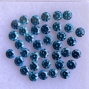 May include: A collection of round, faceted, teal-colored gemstones. The gems are arranged closely together, showcasing their brilliant cut and reflective surfaces. The overall presentation suggests a collection of precious stones, possibly for jewelry making.