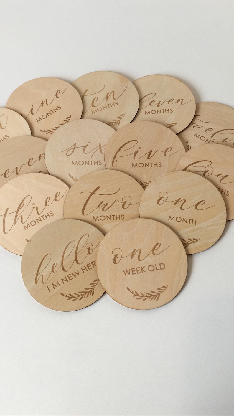 Pu&ograve; includere: Una collezione di segnapunti circolari in legno. Ogni disco &egrave; inciso con un mese o una frase come "hello I'm new here" e "one week old" in elegante scrittura. Il tono naturale del legno e il design semplice creano un'estetica affascinante.